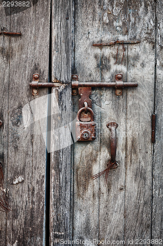 Image of Rusty padlock on an old wooden door of the house