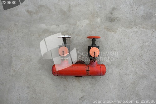 Image of Red iron valve on a cement wall