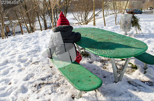 Image of girl sitting childrens playground at green table 