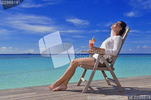 Image of Beautiful young woman with a drink by the sea
