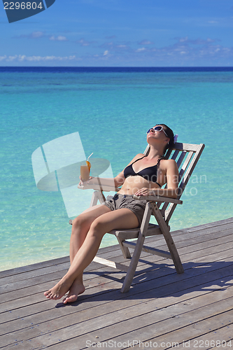 Image of Beautiful young woman with a drink by the sea