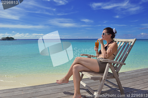 Image of Beautiful young woman with a drink by the sea