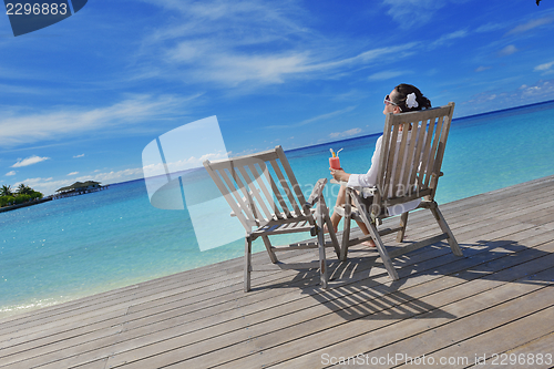 Image of Beautiful young woman with a drink by the sea