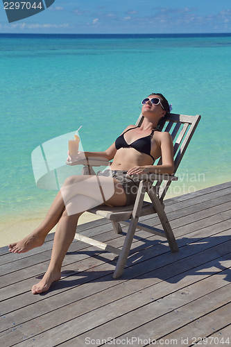 Image of Beautiful young woman with a drink by the sea