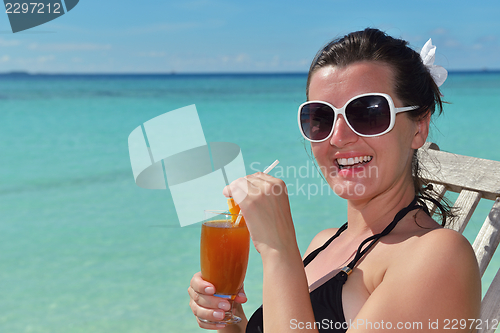 Image of Beautiful young woman with a drink by the sea