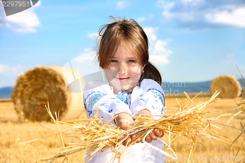 Image of small rural girl on harvest field with straw bales