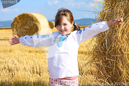 Image of small rural girl on harvest field with straw bales
