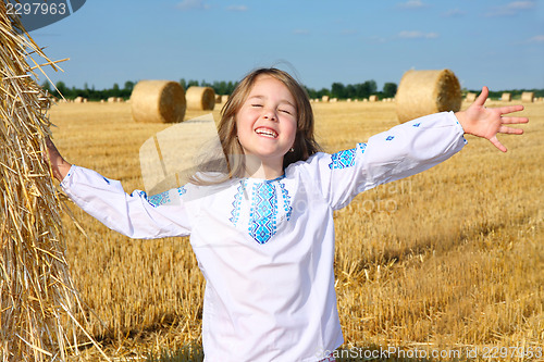 Image of small rural girl on harvest field with straw bales