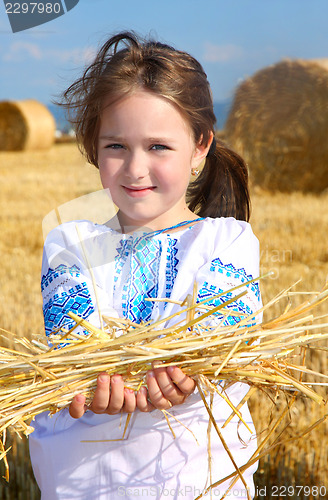 Image of small rural girl on harvest field with straw bales