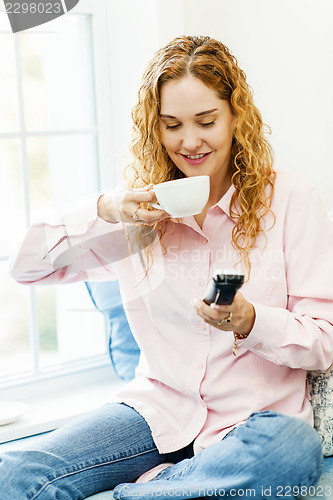 Image of Woman dialing phone and drinking coffee