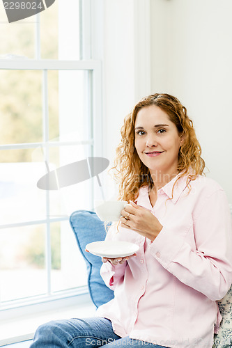 Image of Woman relaxing by the window with coffee
