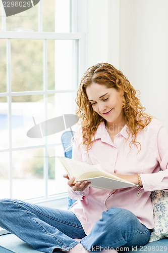 Image of Woman reading book by window