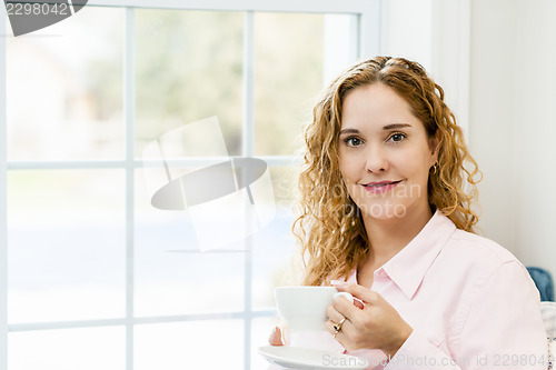 Image of Woman relaxing by the window with beverage