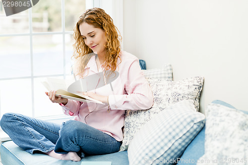 Image of Woman reading book by window