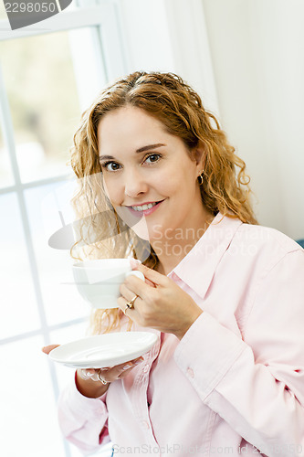 Image of Woman relaxing by the window with beverage