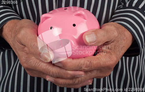 Image of Elderly hand holding piggy bank