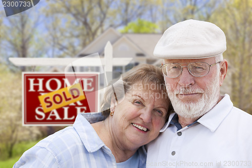 Image of Senior Couple in Front of Sold Real Estate Sign and House