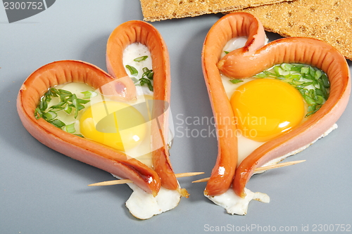 Image of Two sausages in a heart-shaped fried eggs.