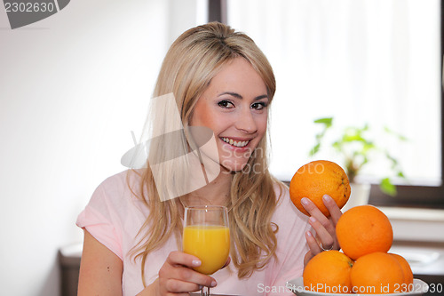 Image of Happy woman with oranges and juice