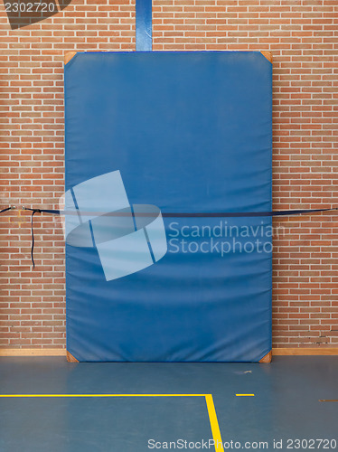 Image of Large blue mat strapped to a brick wall