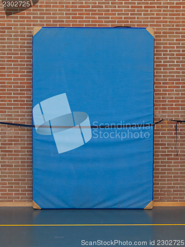 Image of Large blue mat strapped to a brick wall