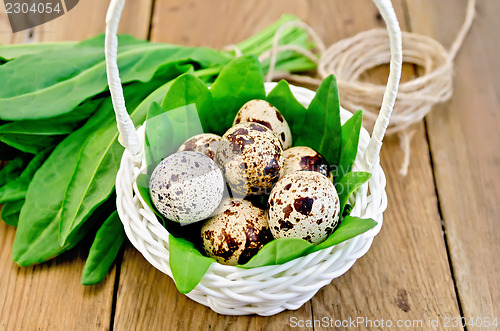Image of Eggs quail in a white basket with sorrel on the board