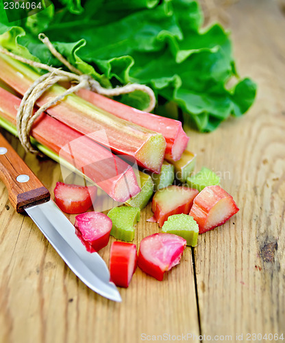 Image of Rhubarb cut with a knife on a wooden board