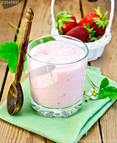 Image of Milkshake with strawberries and spoon on the board