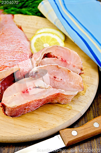 Image of Fillet of sea bass with a knife on a round board