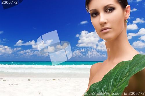 Image of woman with green leaf on tropical beach