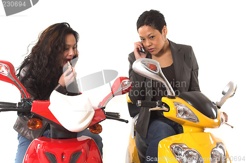 Image of couple girls talking on cell phone and doing make up