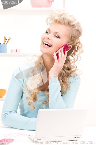 Image of lovely woman with cell phone and computer