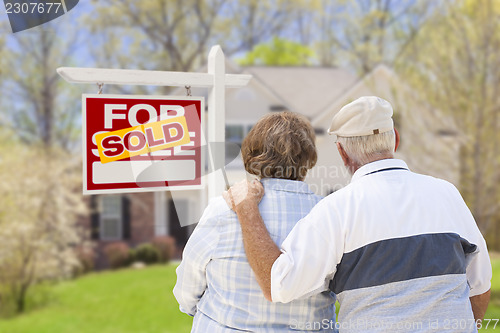 Image of Senior Couple in Front of Sold Real Estate Sign and House