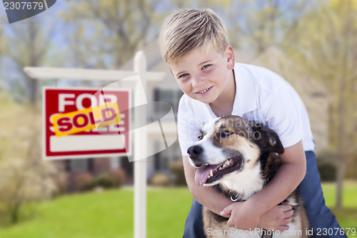 Image of Young Boy and His Dog in Front of Sold For Sale Sign and House