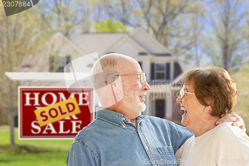 Image of Senior Couple in Front of Sold Real Estate Sign and House