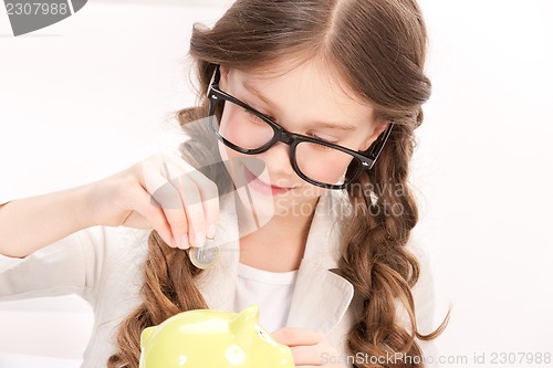 Image of little girl with piggy bank and coin