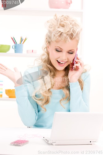 Image of lovely woman with cell phone and computer