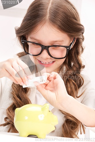 Image of little girl with piggy bank and money