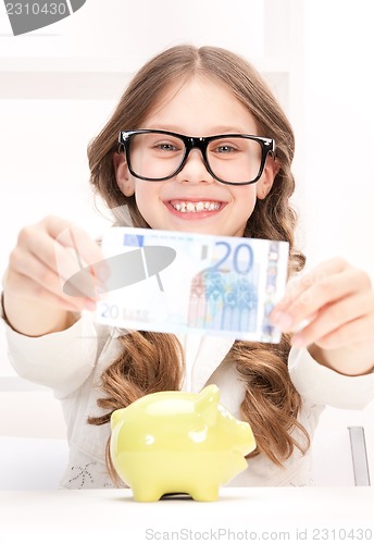 Image of little girl with piggy bank and money