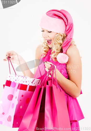 Image of cheerful santa helper girl with shopping bags