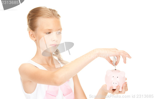 Image of lovely teenage girl with piggy bank and money