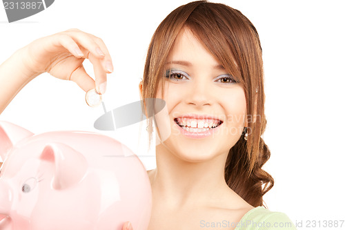 Image of lovely teenage girl with piggy bank and coin