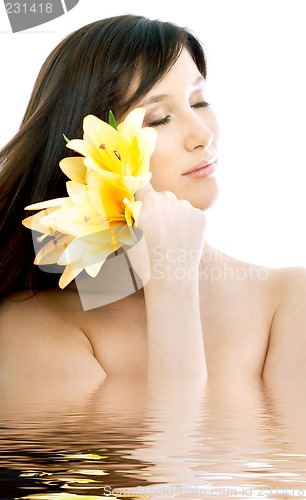 Image of brunette with yellow lily flowers in water