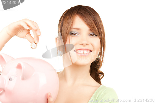 Image of lovely teenage girl with piggy bank and coin