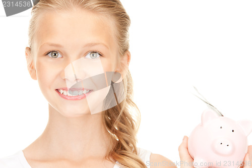Image of lovely teenage girl with piggy bank and money