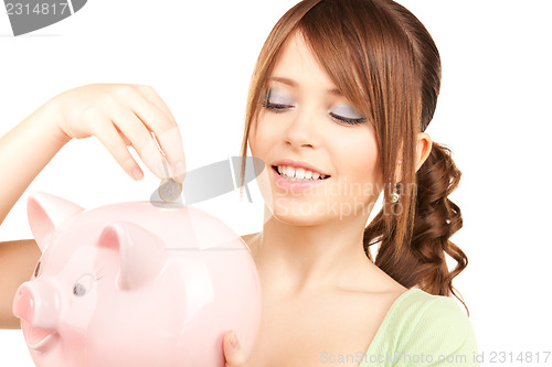 Image of lovely teenage girl with piggy bank and coin