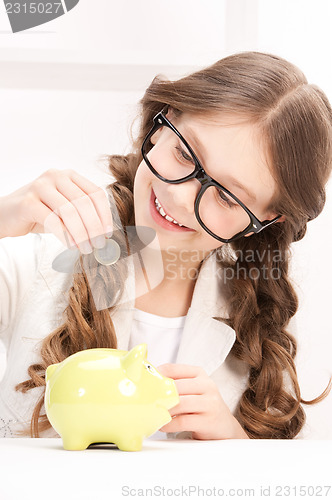 Image of little girl with piggy bank and coin