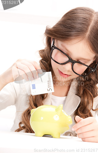 Image of little girl with piggy bank and money