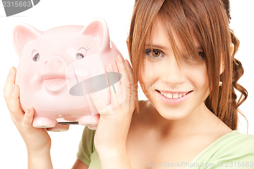 Image of lovely teenage girl with piggy bank