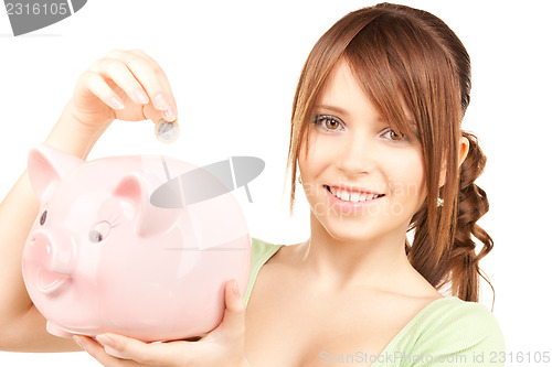 Image of lovely teenage girl with piggy bank and coin